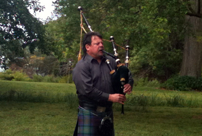 Tim Carey playing bagpipe at the garden